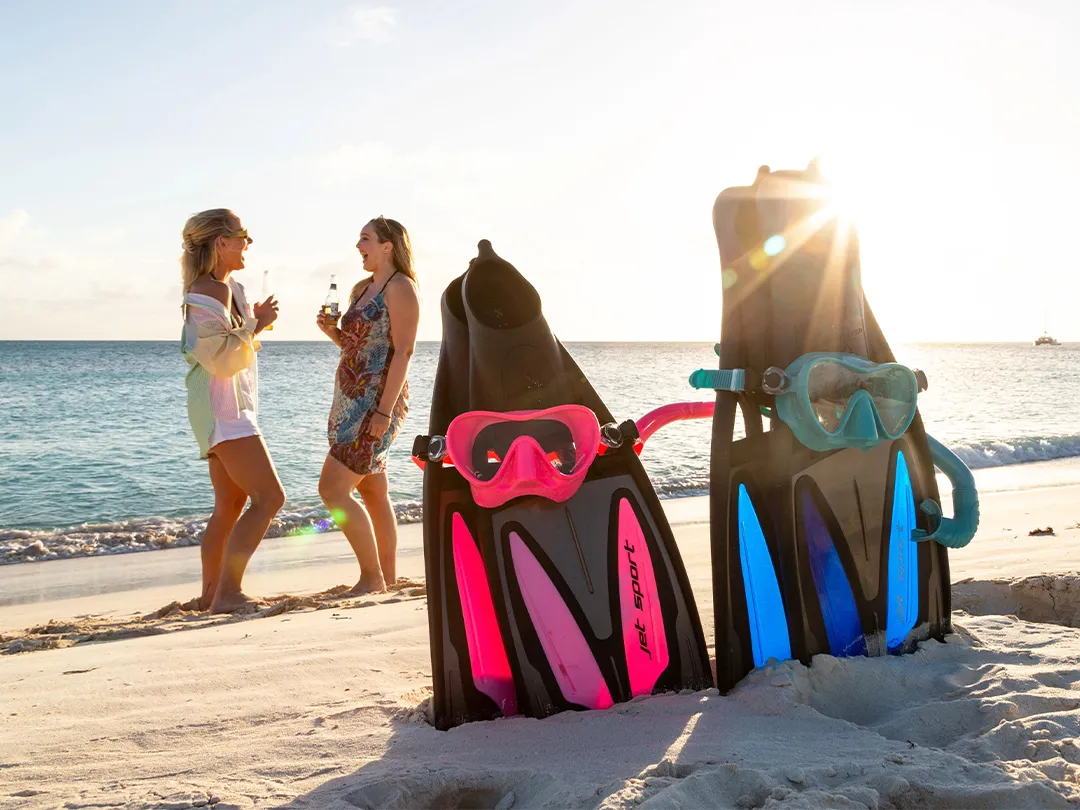SCUBAPRO fins and masks on beach with charter gustes in the background