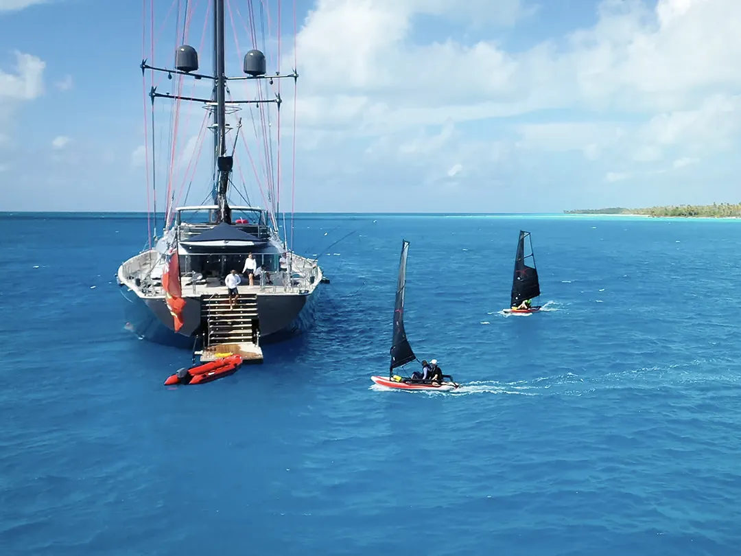 Tiwal dinghys sailing near a yacht